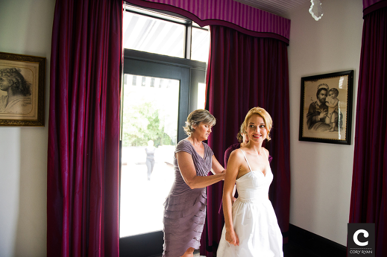 mother helping bride put on wedding dress