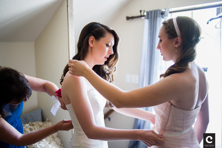 sister and mom helping bride get dressed