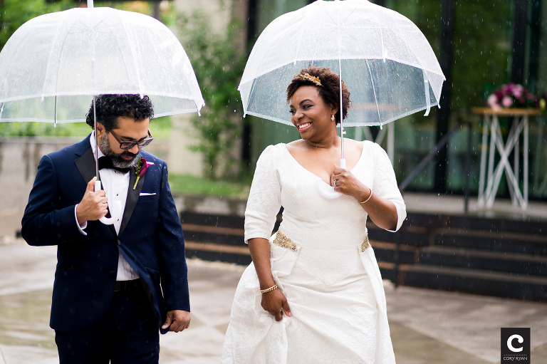 bride and groom with umbrellas in the rain