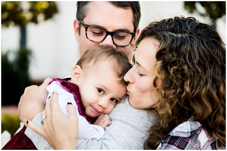 mom kissing her infant daughter in family photo